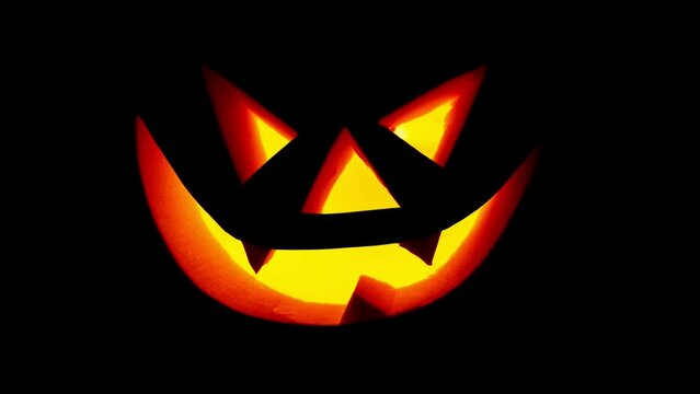 Scary face on blinking on black background. Jack-o-lantern glowing in the dark. Halloween pumpkin