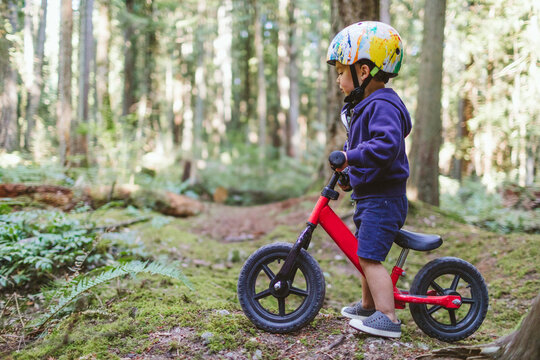 Side view of toddler biking through a forest.