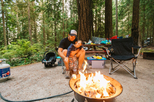 Dad and son roasting marshmallows over propane fire at campsite