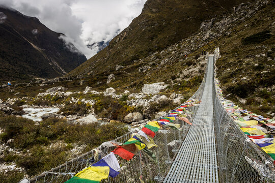 Mountain valley with prayer flag lined swing bridge
