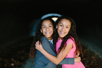 Twin sisters embrace and smile for a portrait