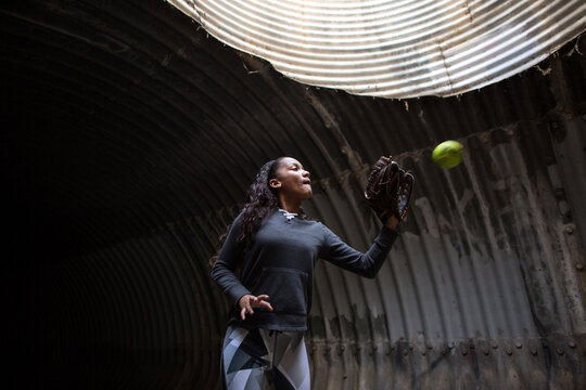 Girl prepares to catch a softball in her glove while in a tunnel