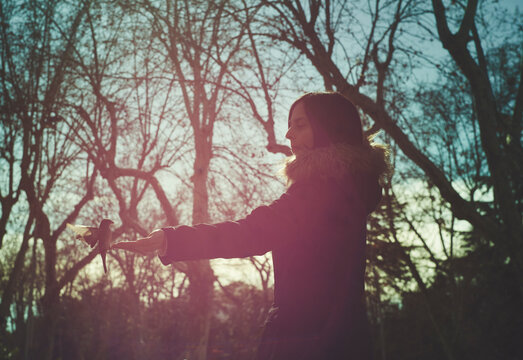 Woman smiling at bird outdoors