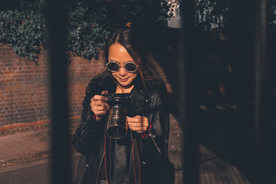 Asian woman taking photos with a camera on the street