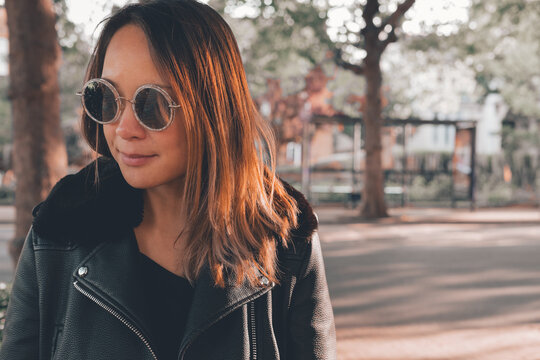 Portrait of asian woman wearing sunglasses on the street around trees