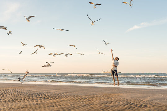 Boy jumping to feed seagulls at the beach in Galveston, Texas