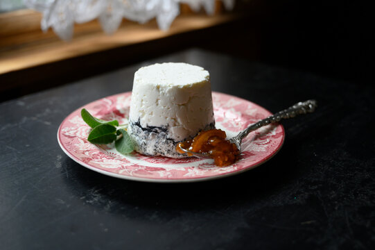 Homemade goat cheese with herbs and spoon filled with fresh marmalade