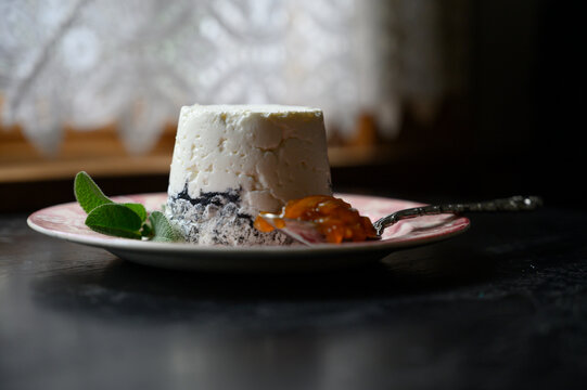 Side view of handmade goat cheese on plate with herbs and marmalade