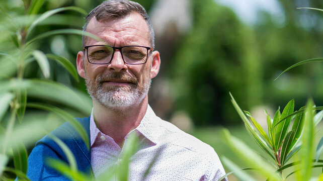 Front View Of Bearded Adult Man Hidden Behind Foliage Looking Camera