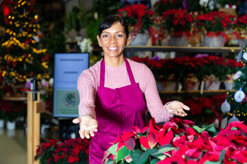 Latin woman home plants store worker standing in salesroom during christmas sale, showing inviting...