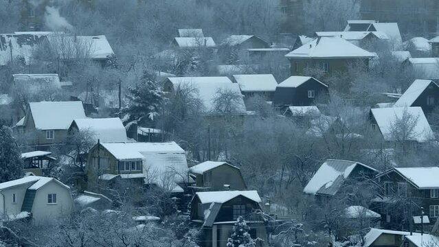 Private houses in winter on the border with a big city, with roofs covered with a layer of snow
