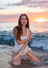 Fototapeta na wymiar Attractive woman posing in the surf at sunset