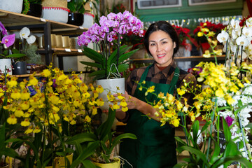 Portrait of a confident and successful Asian florist woman standing in a shop with flowers in her hands