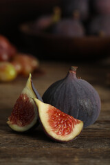 Whole and cut tasty fresh figs on wooden table, closeup
