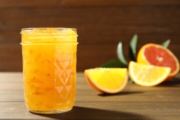 Delicious orange marmalade and fresh fruits on wooden table. Space for text