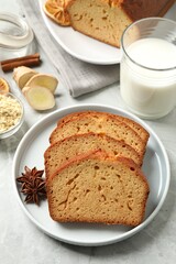 Slices of delicious gingerbread cake served with milk on light grey table