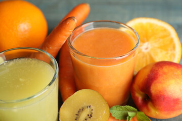Glasses of delicious juices and fresh ingredients on table, closeup