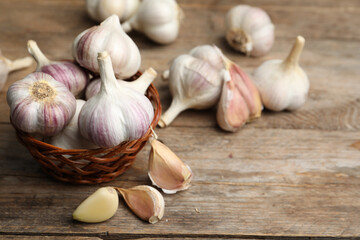 Fresh organic garlic in wicker basket on wooden table. Space for text
