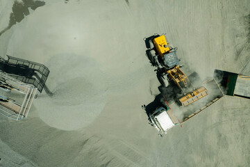 aerial view of sand loaders are shoveling rocks into dump trucks
