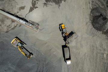 aerial view of sand loaders are shoveling rocks into dump trucks