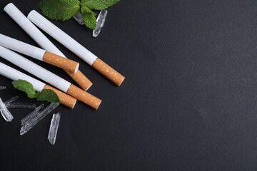 Cigarettes, menthol crystals and mint on black background, flat lay. Space for text