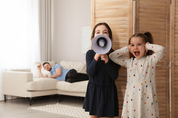 Cute little children with megaphone waking up their father at home