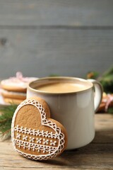 Tasty heart shaped gingerbread cookie and hot drink on wooden table, closeup