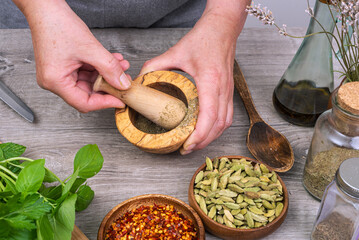 female hands grind spices in a mortar on the kitchen table.