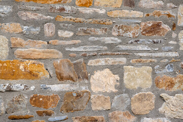 Close up of old stone wall with thick grout and rough textured surface.