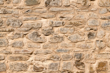 Close up of old stone wall with thick grout and rough textured surface.
