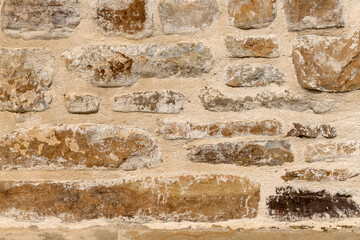 Close up of old stone wall with thick grout and rough textured surface.