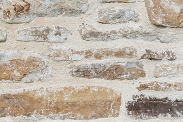 Close up of old stone wall with thick grout and rough textured surface.