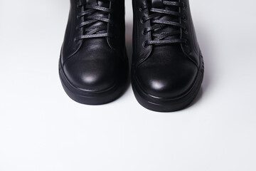 Defocus black leather male shoes, white background. Men’s ankle boot leather isolated on white background, closed up. Winter boots. Closeup. Out of focus