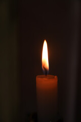 Fototapeta na wymiar Defocus close up single candle light and flame on black background. Vertical. RIP flame. Memory. Out of focus