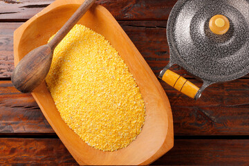 Raw cornmeal flour used in polenta, in wooden bowl over rustic wooden table