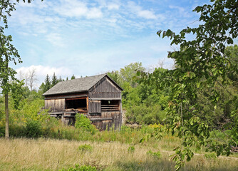 Old Sawmill Wooden Building in country, partly clouded sky with trees.