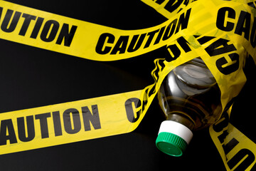 Bottle of vegetable oil (seed oils) wrapped in caution tape concept for unhealthy ultra processed foods, dietary waring for increased risk on inflammation and pro inflammatory omega six fatty acids - obrazy, fototapety, plakaty