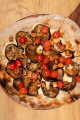 Vegetarian cuisine. Closeup view of a pizza with mozzarella cheese, cherry tomatoes and roasted eggplant.