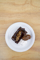 Sweet desserts. Closeup view of a bittersweet chocolate flan with vanilla cream and dulce de leche, in a white dish on the wooden table.