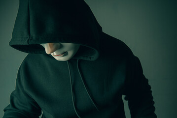 A portrait of an anonymous hacker wearing a mask and a black hoodie sitting bear and scary. Hacking...