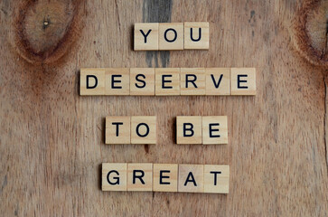 you deserve to be great text on wooden square, motivation quotes
