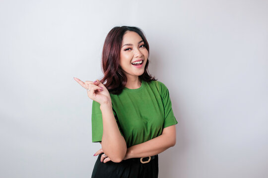 Smiling beautiful Asian woman pointing finger sideward to empty space isolated white background