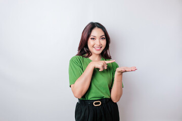 Fototapeta premium Smiling beautiful Asian woman pointing finger sideward to empty space isolated white background