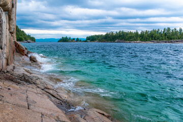 A rocky hiking trail leads along a cliff right at the edge of Lake Superior to some Indigenous...