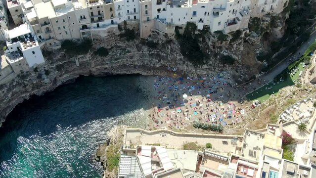 Drone zooms in Polignano a Mare beach in Italy and crystal blue water of Adriatic sea can be seen