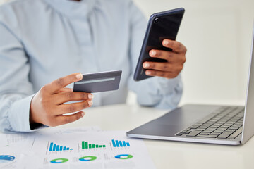 Finance, accounting and trading with a businessperson using a phone and credit card in her hands and a graph on the desk. Fintech, investment and banking with a female employee managing money online