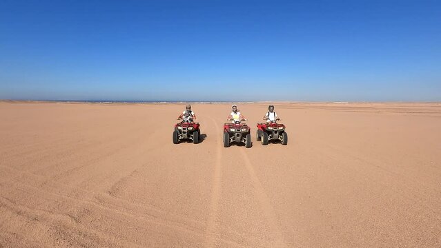 On quad bikes on sand dunes. The family rides quad bikes in the desert