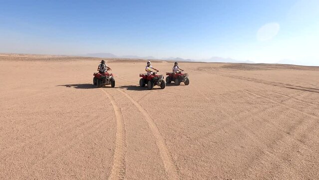 A happy family rides quad bikes in the desert. Quad bike ride