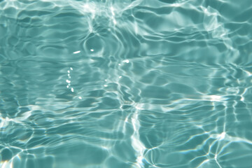 Bluewater waves on the surface ripples blurred. Defocus blurred transparent blue colored clear calm water surface texture with splash and bubbles. Water waves with shining pattern texture background.
