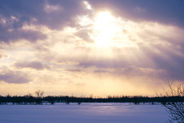Fototapeta na wymiar Sunset on a cloudy day on the snow fields near Saint Bruno de Montarville in Quebec, Canada